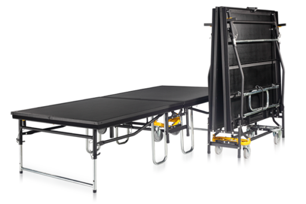 Escenario plegable móvil con ruedas para eventos, mostrando un módulo desplegado y varios paneles plegados en almacenamiento vertical.